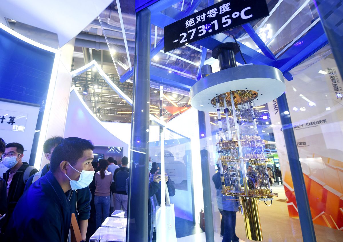 A person in a mask attending a tradeshow looks at a quantum computing hardware in a display case with Chinese writing.