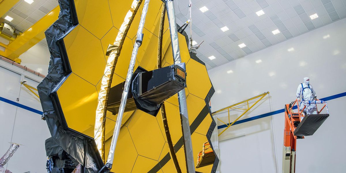 a person on a cherry picker next to the james webb space telescope