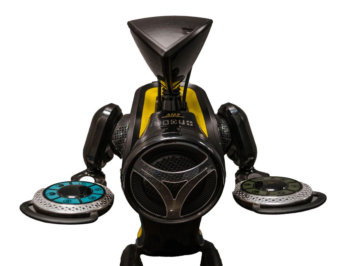 A photo of a black two wheeled balancing robot with a triangular head, a speaker for a torso, and controls on its arms, called AMP