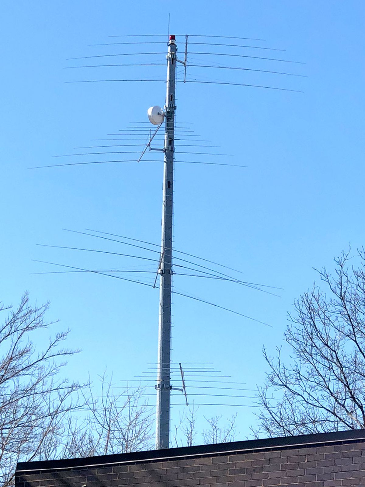 A photo of a cell tower with multiple levels of antennas sticking out of it.