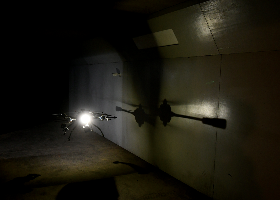 A photo of a flying drone hovering in a dark area.  