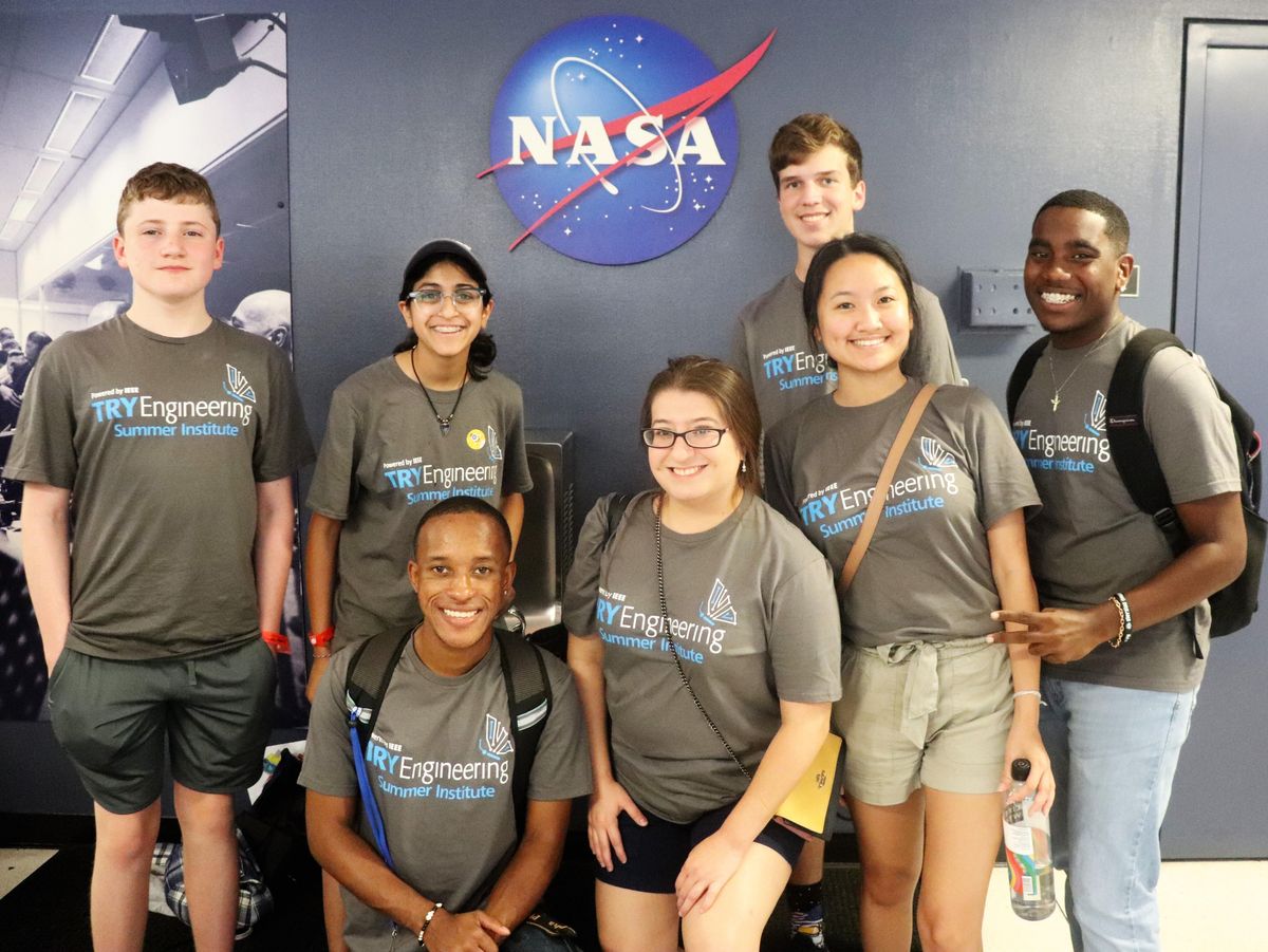 A photo of a group of people standing in front of a wall with a NASA logo on it.  