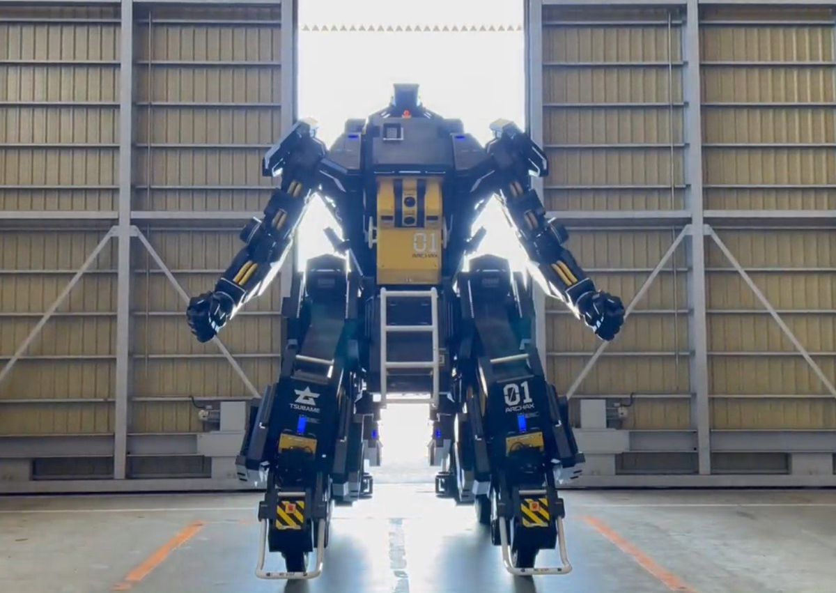 A photo of a huge robotic vehicle with arms, standing inside a warehouse