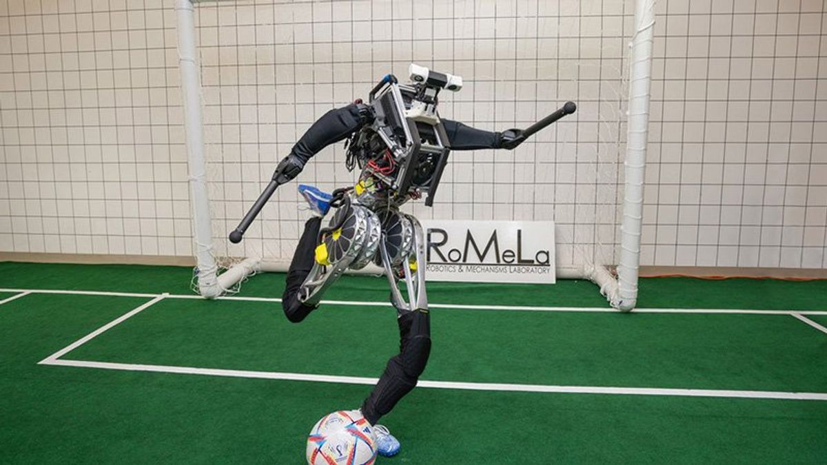 A photo of a humanoid robot in the act of kicking a soccer ball while in front of a goal.