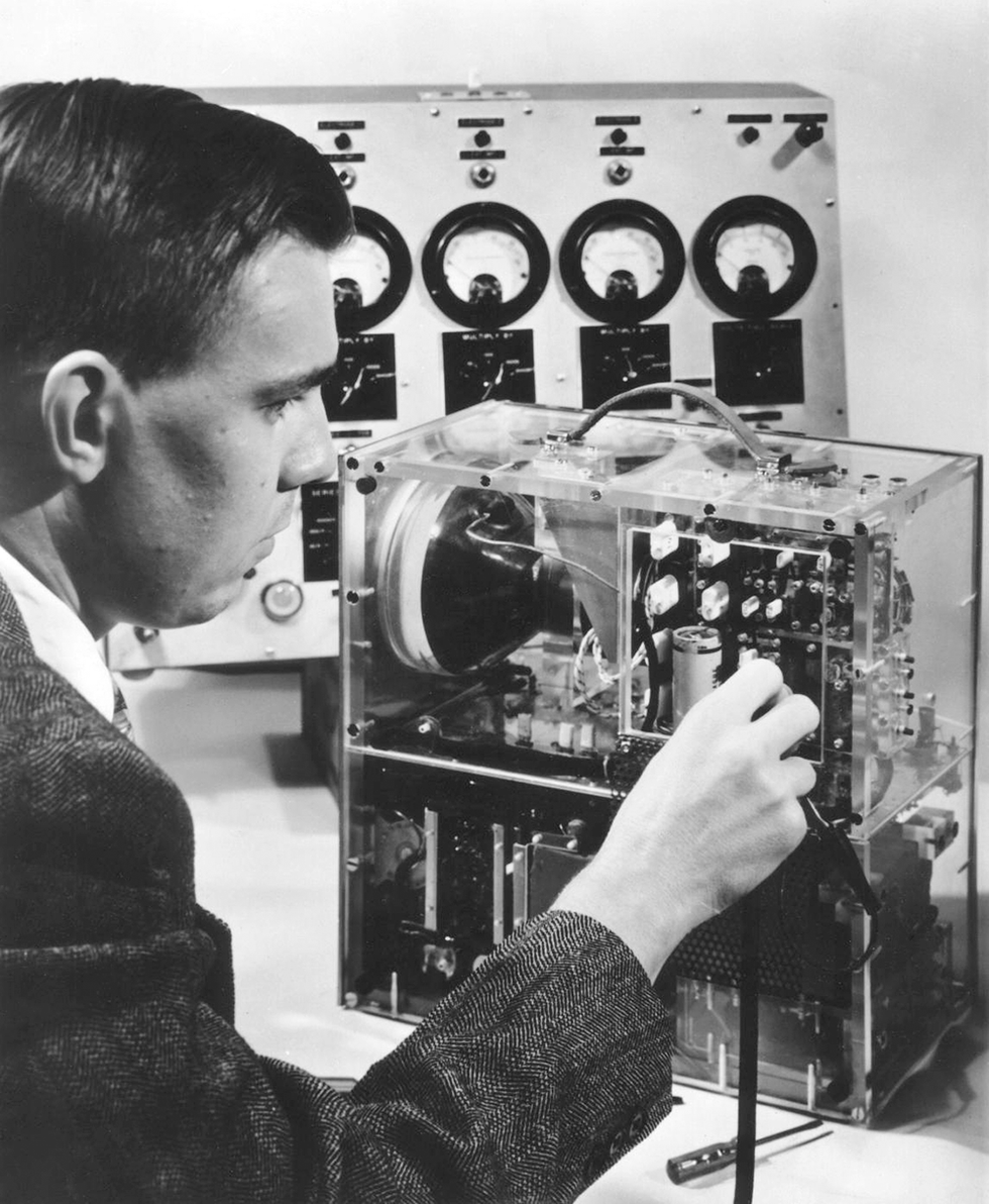 A photo of a man in a jacket placing a transistor in a device.