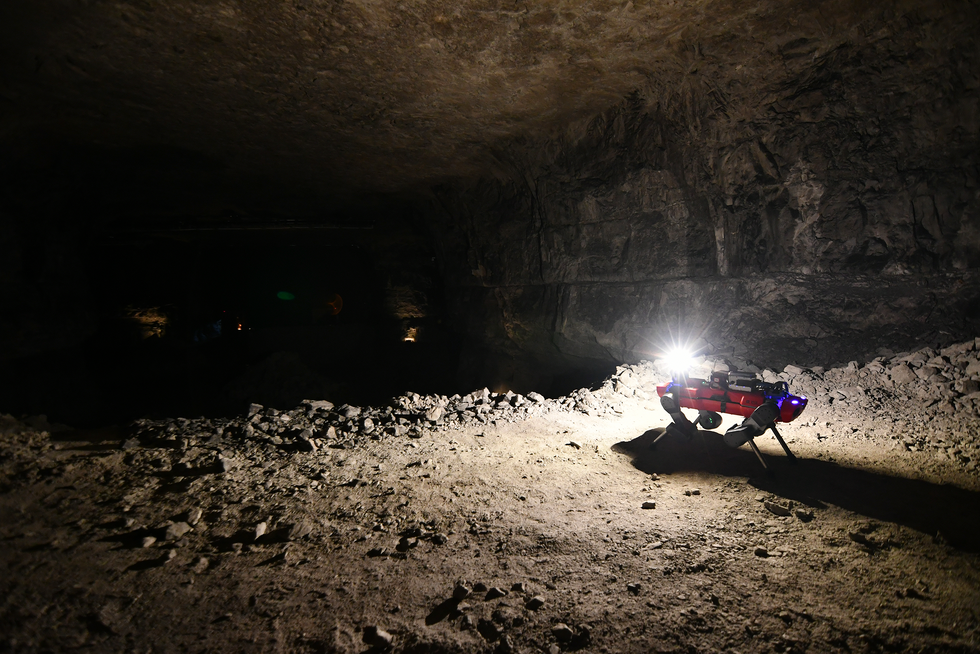 A photo of a quadruped robot lighting up a cavern. 