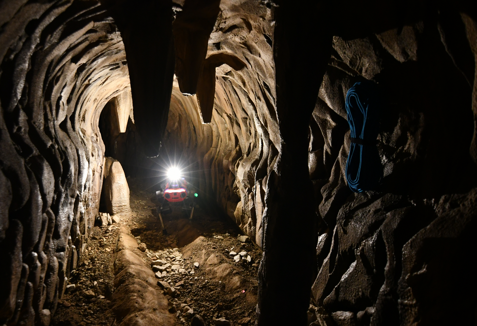 A photo of a quadruped robot moving through a cavern.  