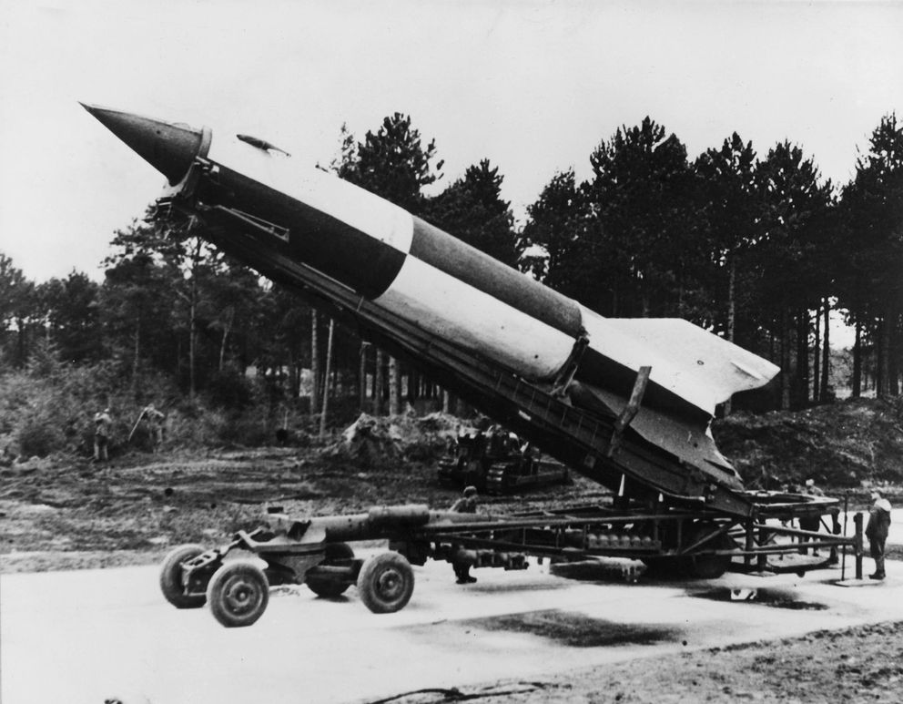 A photo of a rocket on a launcher with trees in the background. 
