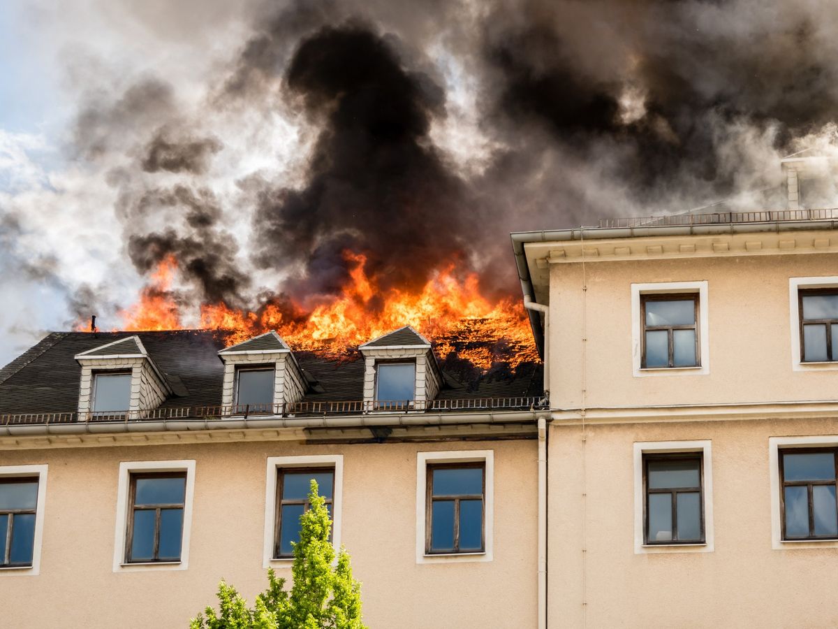 A photo of a two-story building with flames coming from its roof