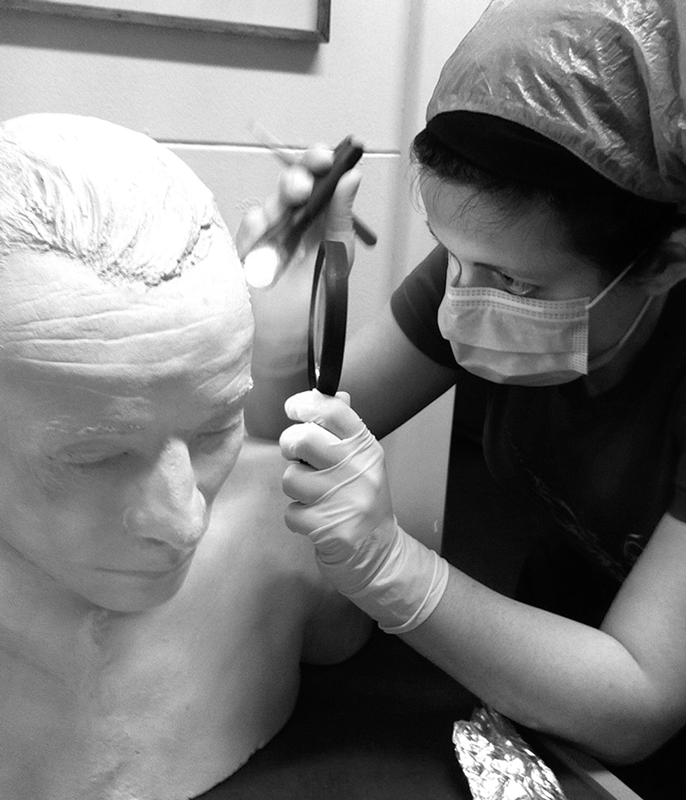 A photo of a woman next to a plaster cast of a man.