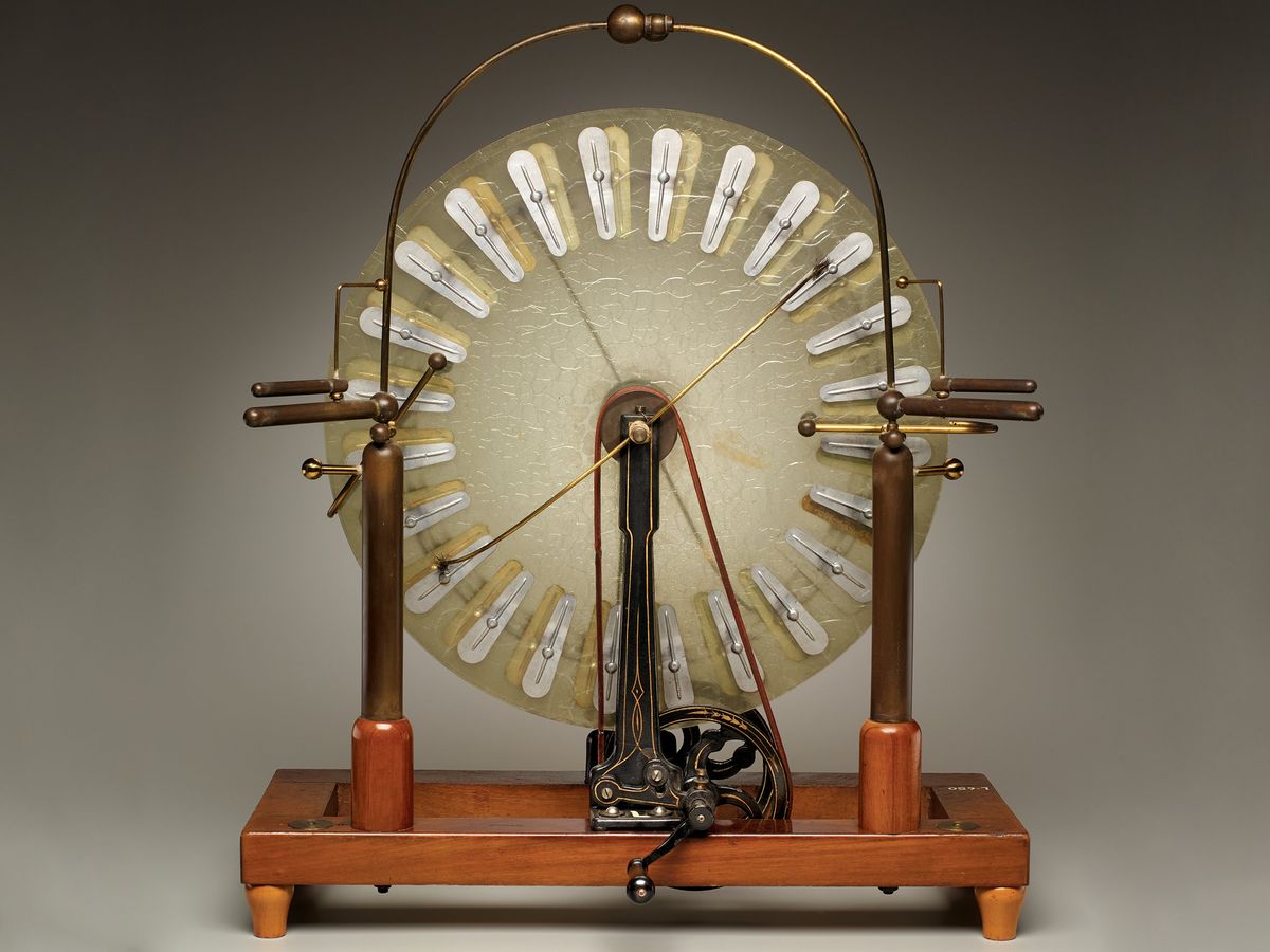 A photo of an antique contraption having glass disks, a wooden base, and supporting wires.