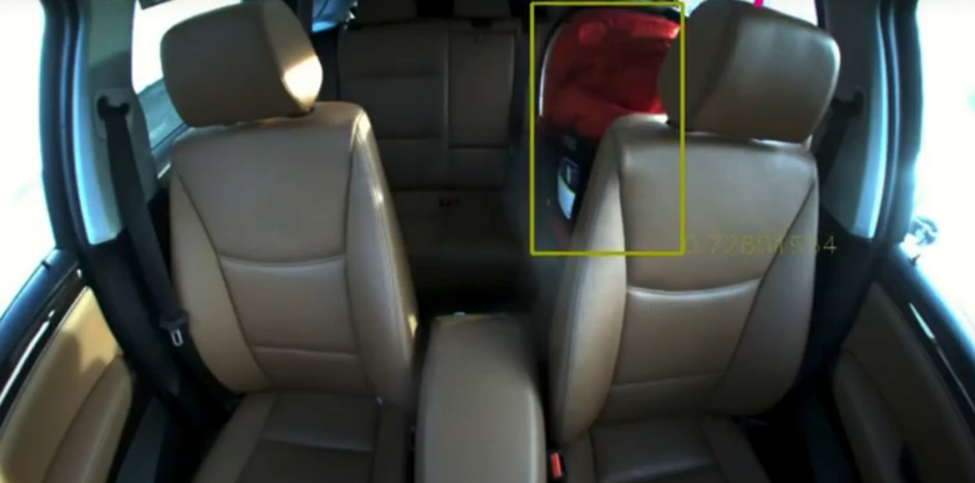 A photo of an inside of a car with a yellow square around a car seat in the back.