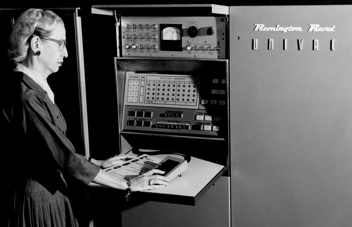 A photo of an older woman in front of an early generation computer. 