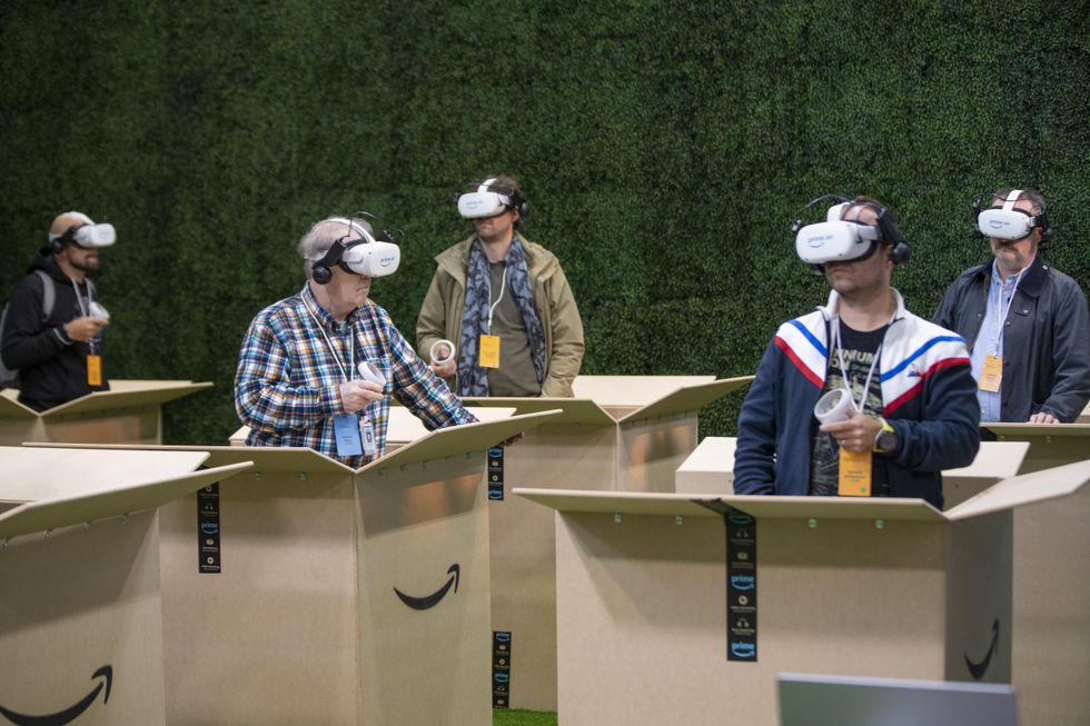 A photo of men with VR goggles on while standing in amazon boxes.