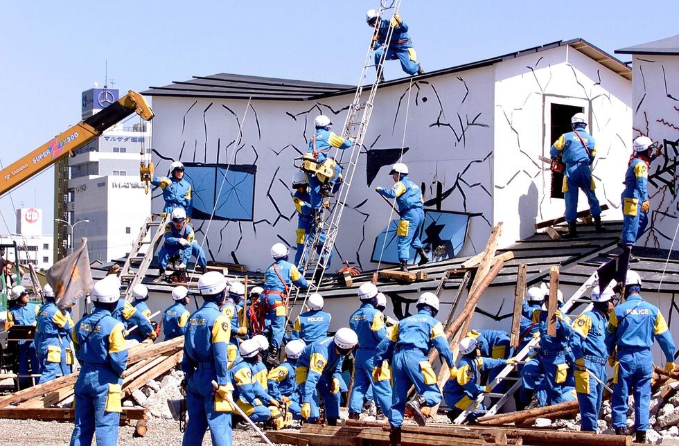 A photo of people in blue uniforms and helmets surrounding a building.