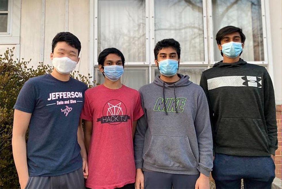 A photo of the four young males wearing surgical masks standing in front of windows of a house.