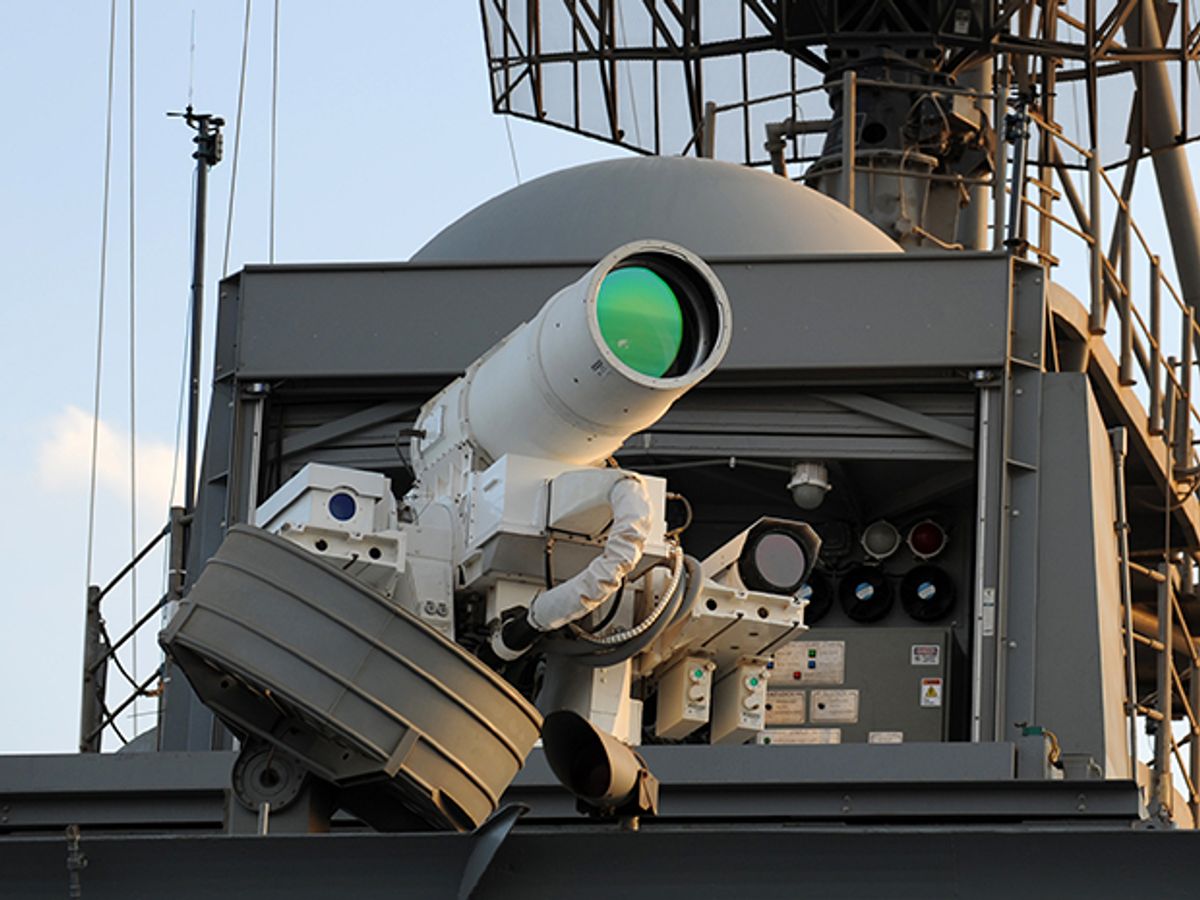 A photo of the laser weapon mounted on the USS Ponce, which looks like a white telescope pointing out from high on the ship.
