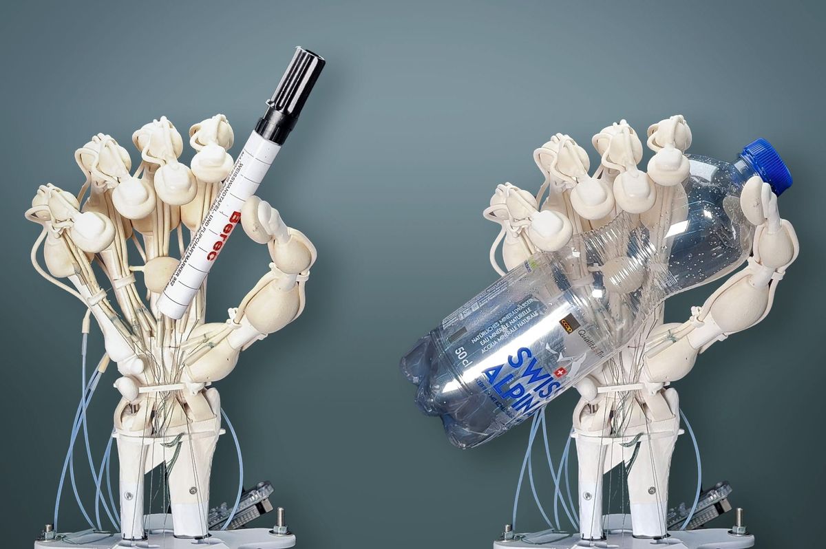A photo of two plastic robot hands with knobbly joints, holding a pen and a water bottle.