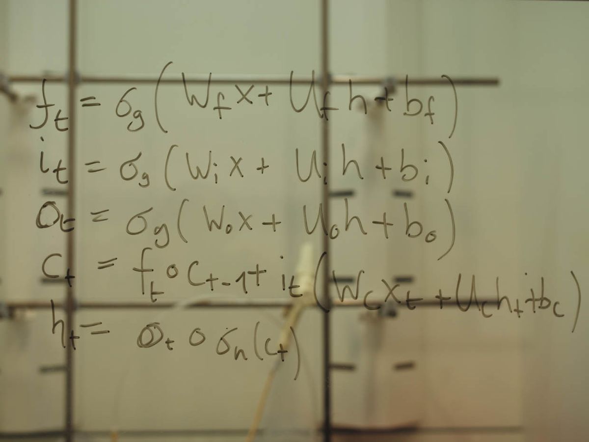 A photo shows equations drawn on a transparent blackboard.