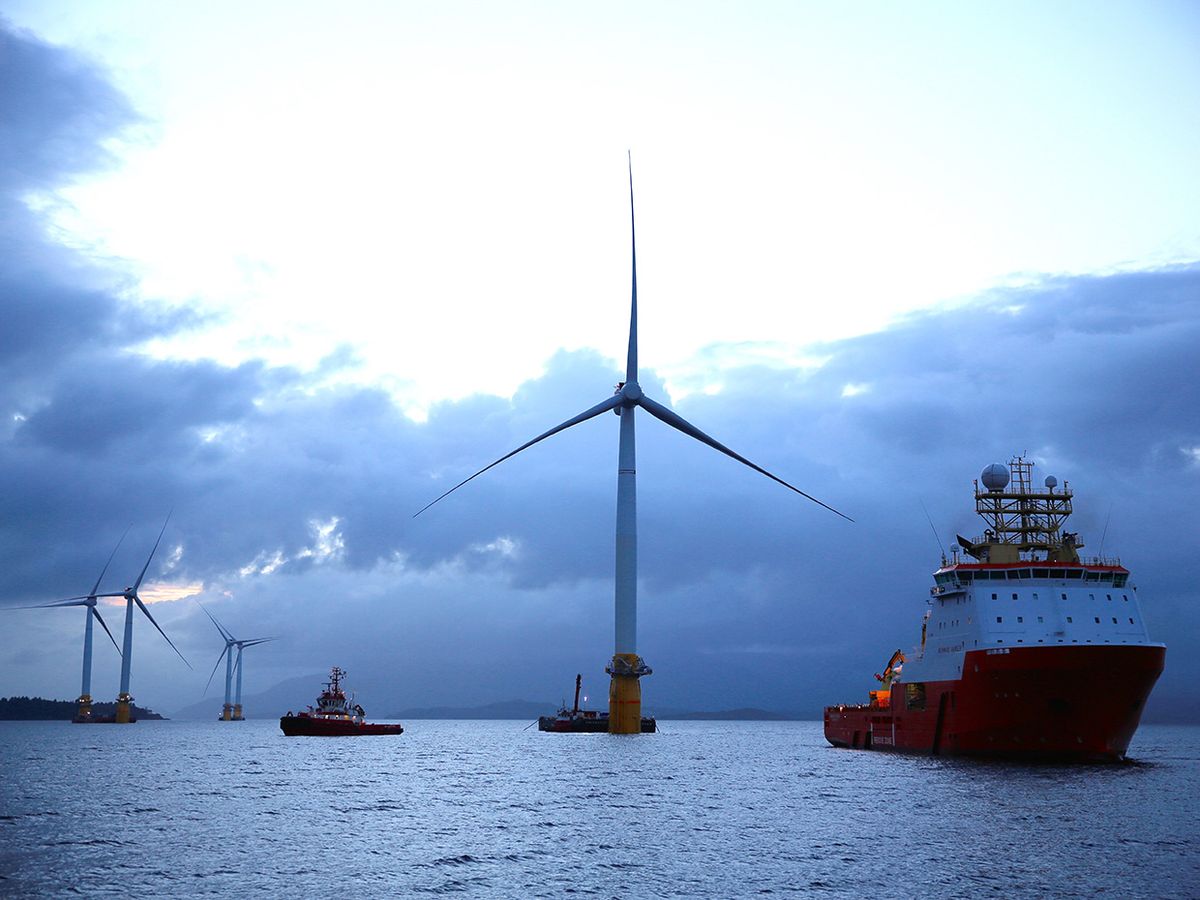 A photo shows several of Statoil's floating wind turbines surrounded by ships at dusk. 