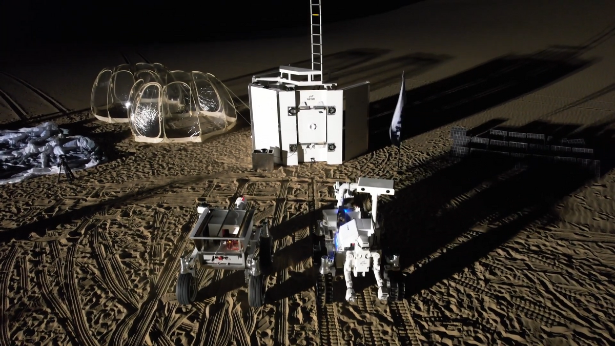 A photo taken from a drone of a group of robotic rovers being tested in a desert at night