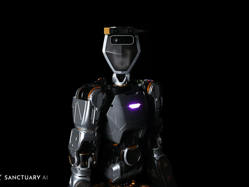 A photograph of a futuristic looking dark colored angular humanoid robot from the waist up