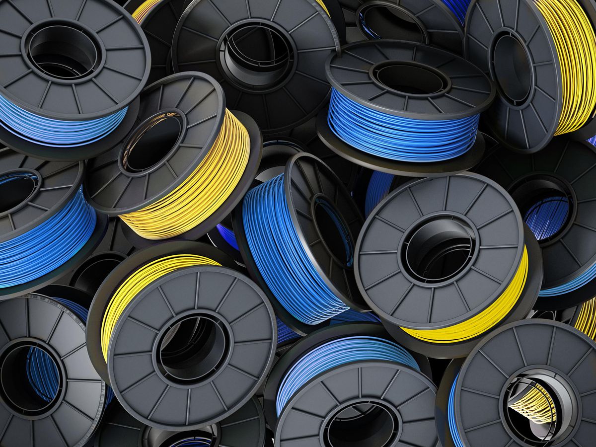 A pile of yellow and blue 3d printing filament spools 
