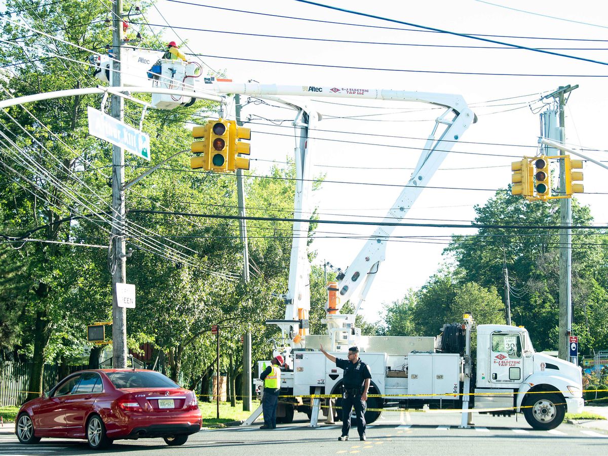 A police officer directs traffic as a Con Edison crew works to restore power due to Tropical Storm Isaias in Staten Island, New York.