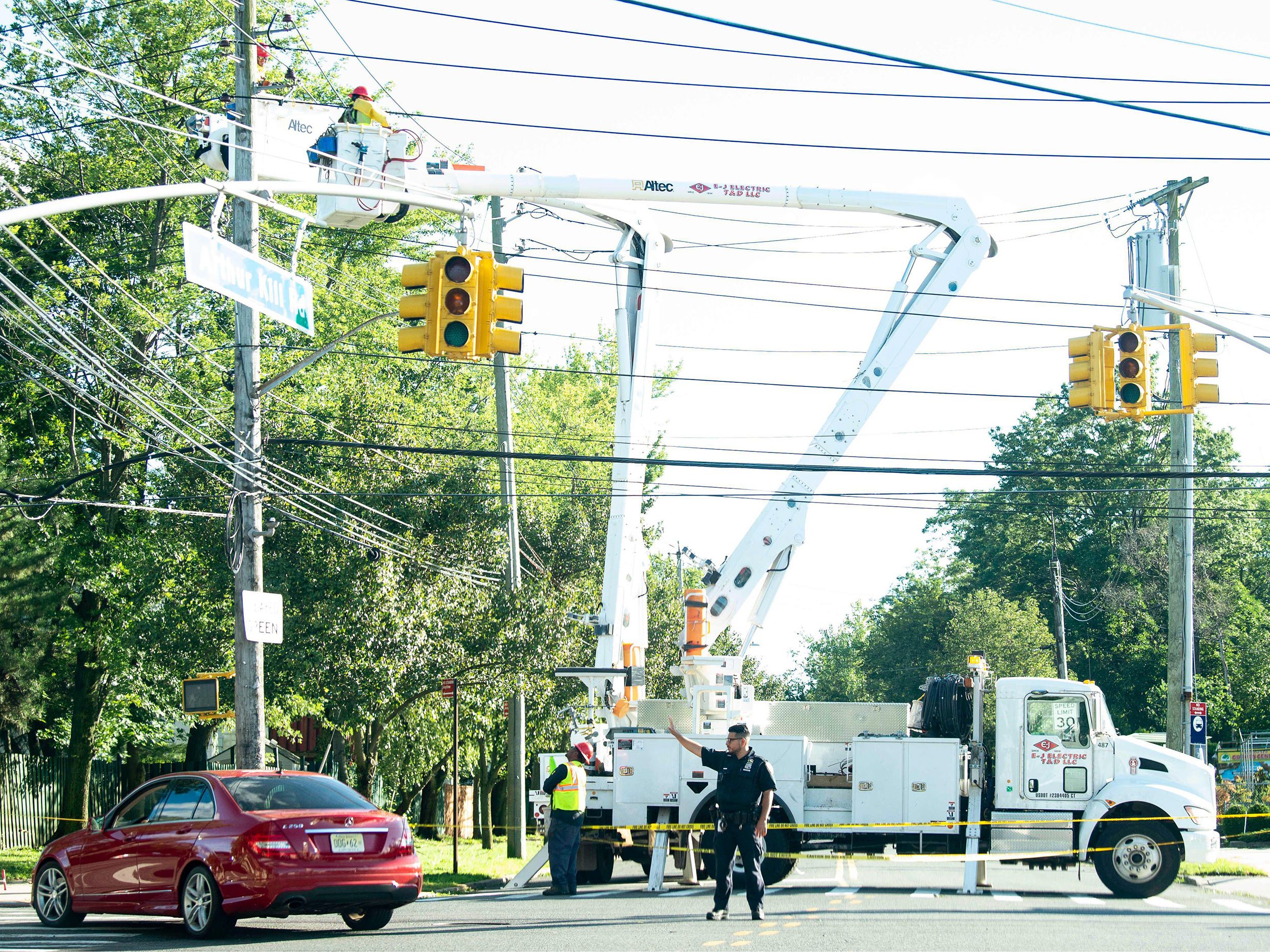 A police officer directs traffic as a Con Edison crew works to restore power due to Tropical Storm Isaias in Staten Island, New York.