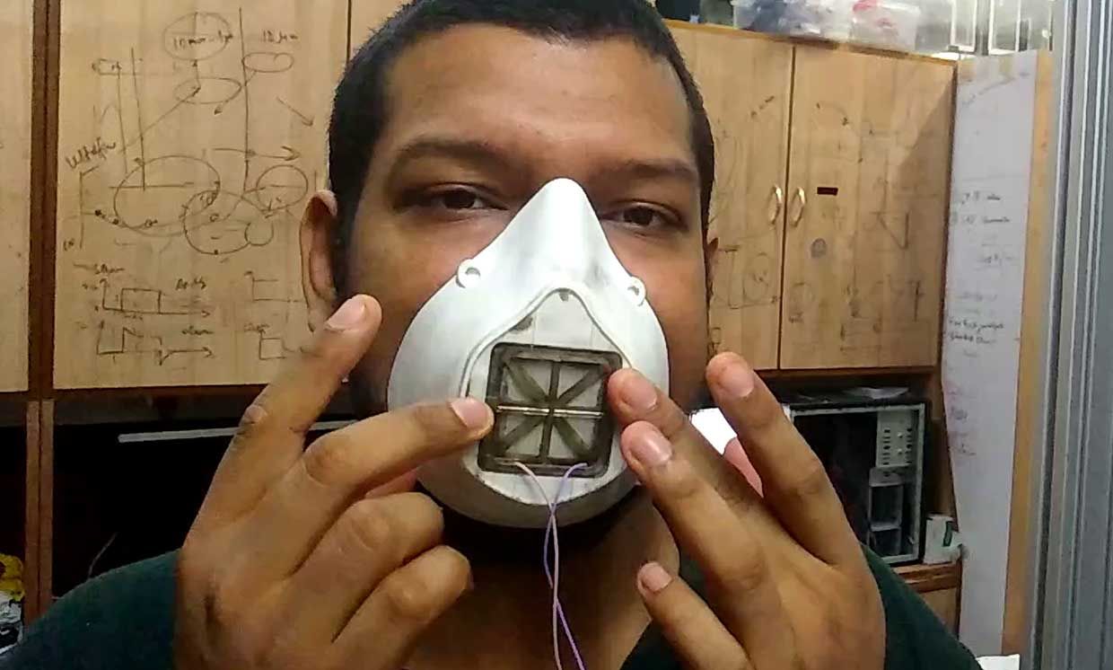 Photograph of a man with a prototype battery-operated smart mask maintains 95% filtration efficiency by continuously charging a filtration cartridge.
