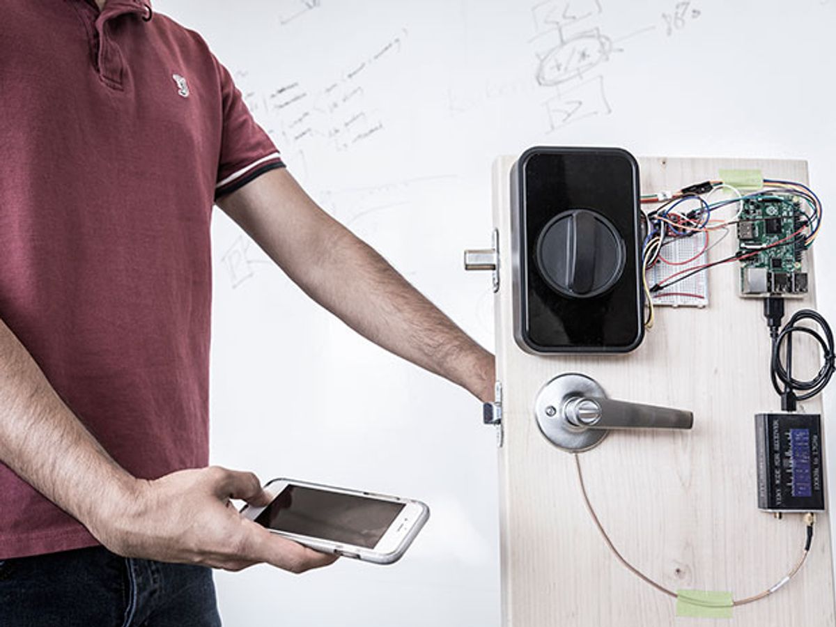 A researcher holds their thumb to the fingerprint sensor of a smartphone and touches a door handle at the same time.