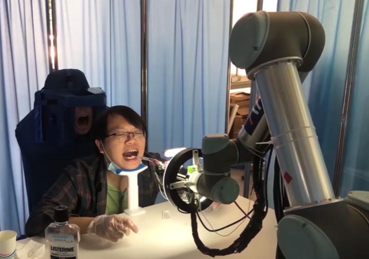 A robot arm moves a complex sampling attachment into the open mouth of a human volunteer