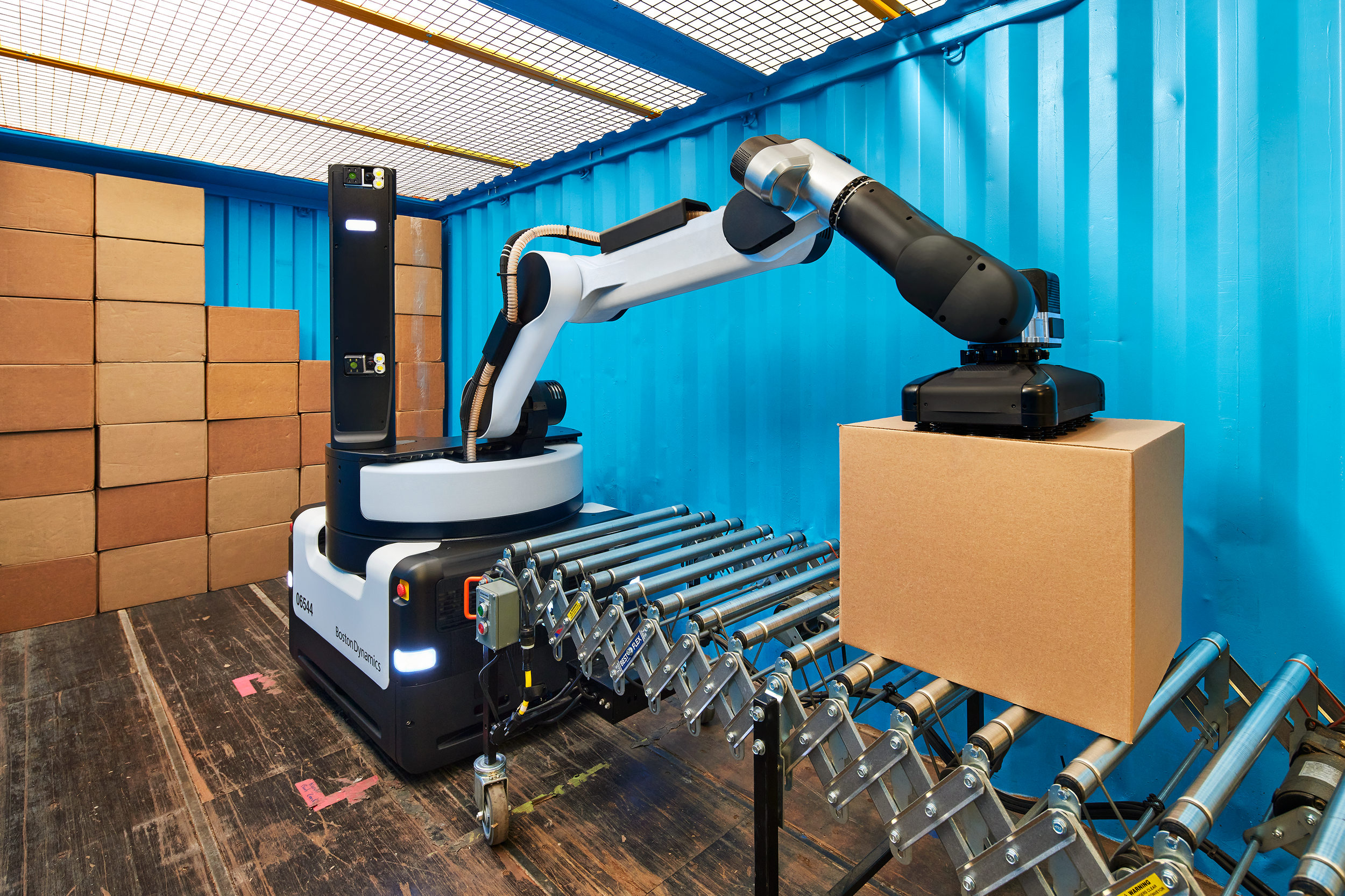 A robot near a conveyor belt with a box being placed by the robot. 