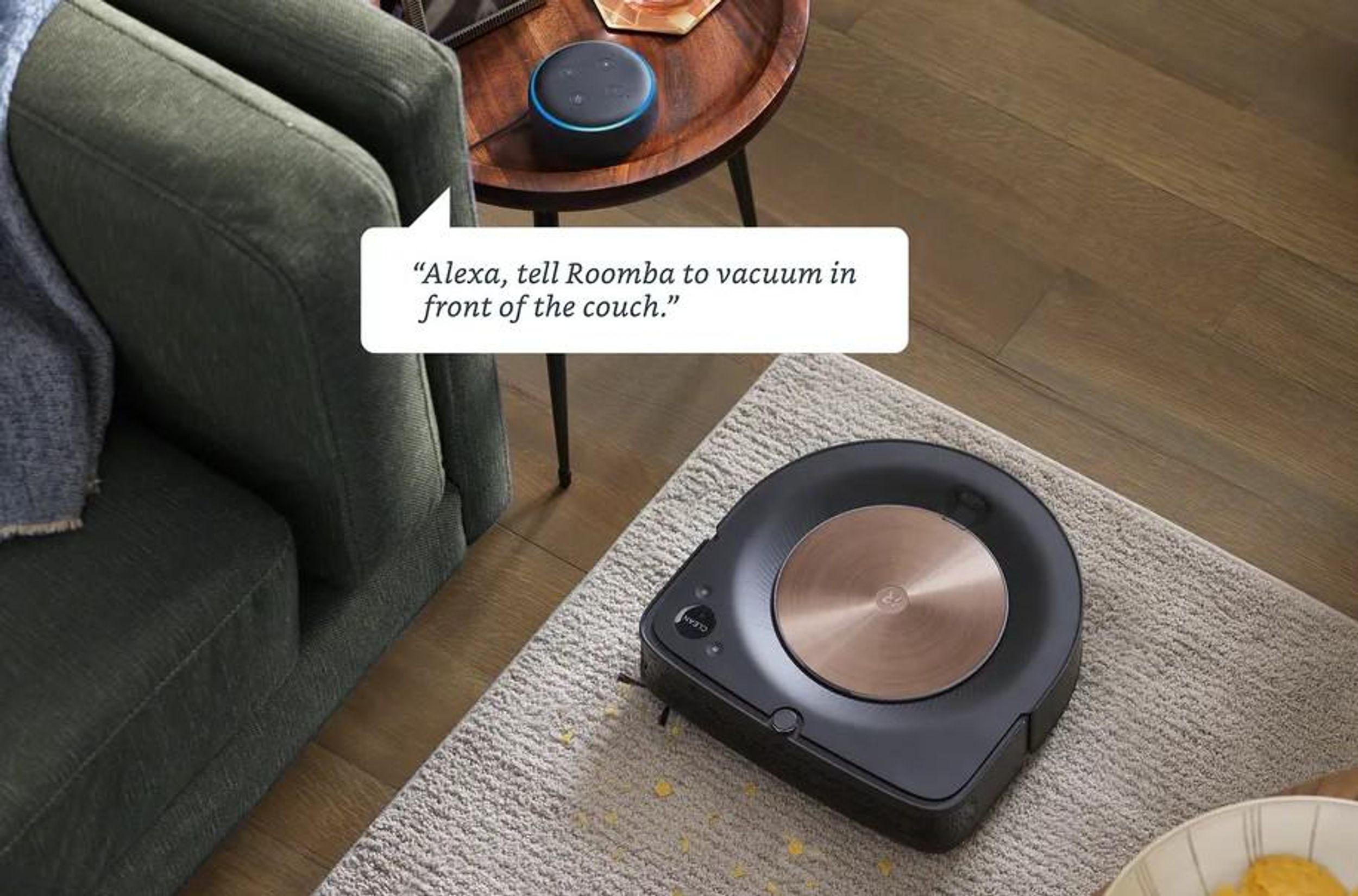 A robot vacuum cleans a dirty carpet while an Amazon Alexa on a nearby table provides instructions