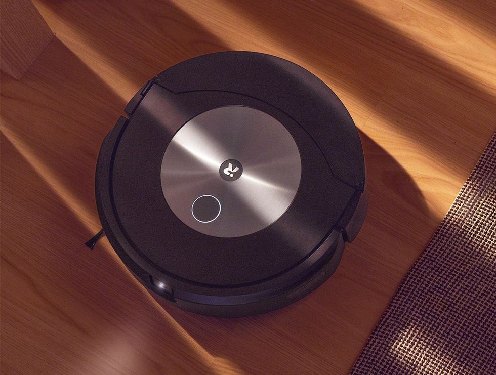 A round robot vacuum traverses hardwood floors and carpet
