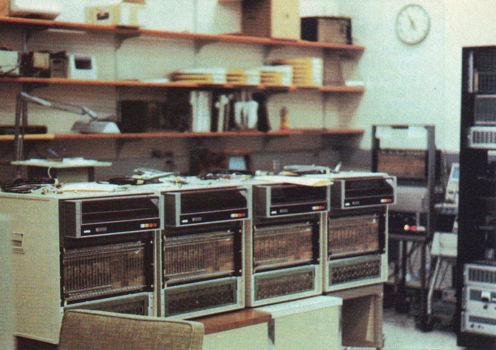 A row of four computers in a supply room