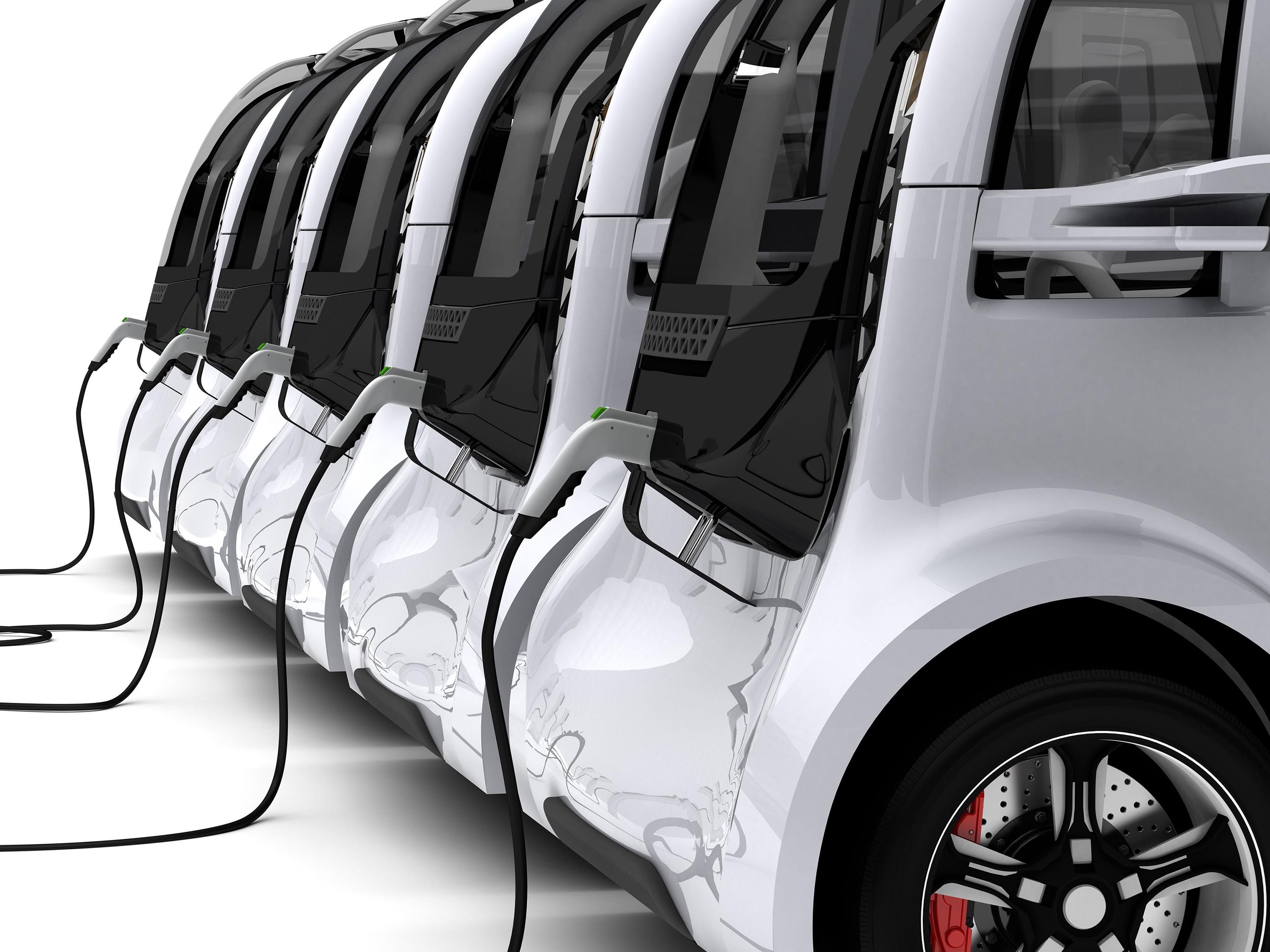 A row of gray and black electric cars, with plugs running from their rear off to the left side of the image.