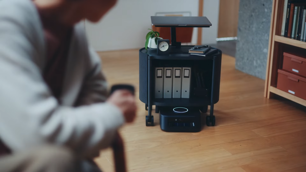 A small black wheeled robot drives underneath a wheeled shelf and carries it into a living room