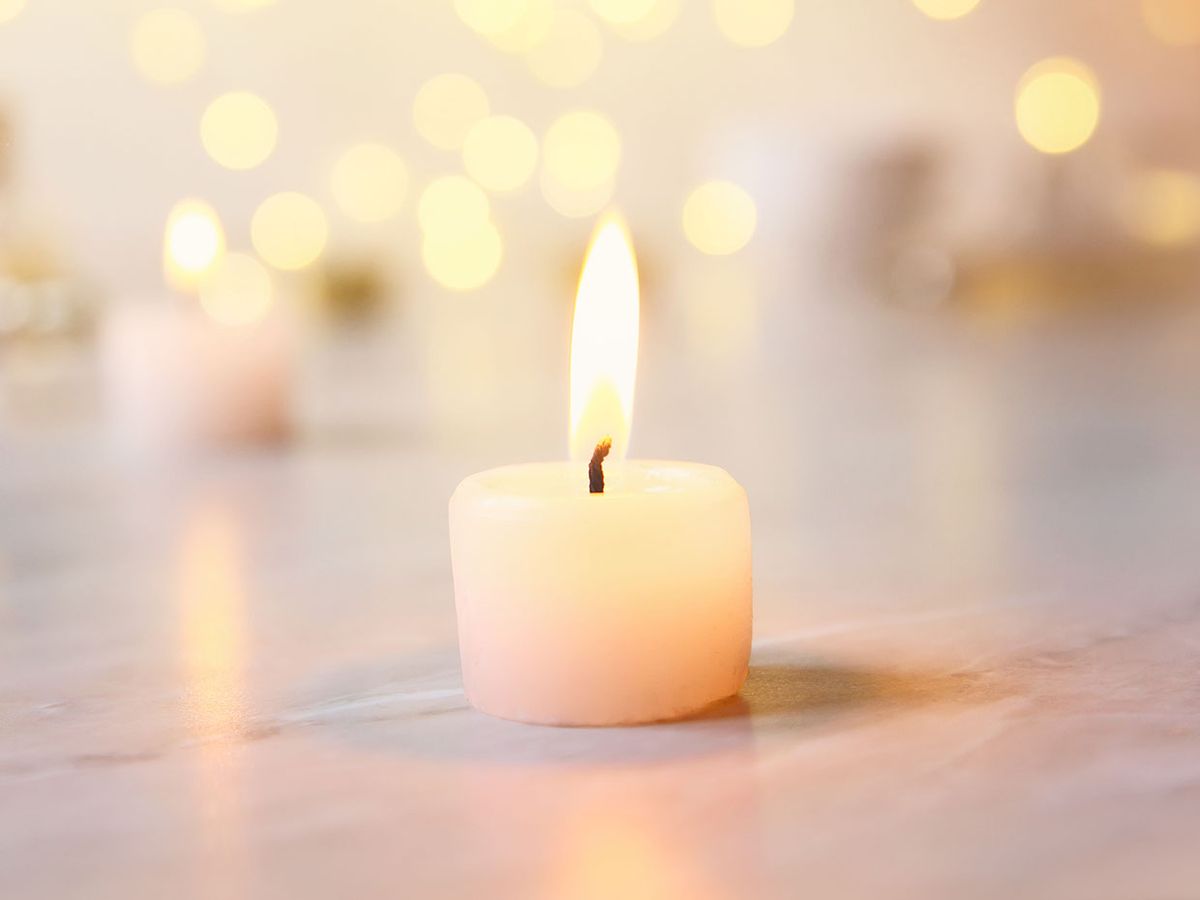 A small candle burns, with many more blurry in the background.