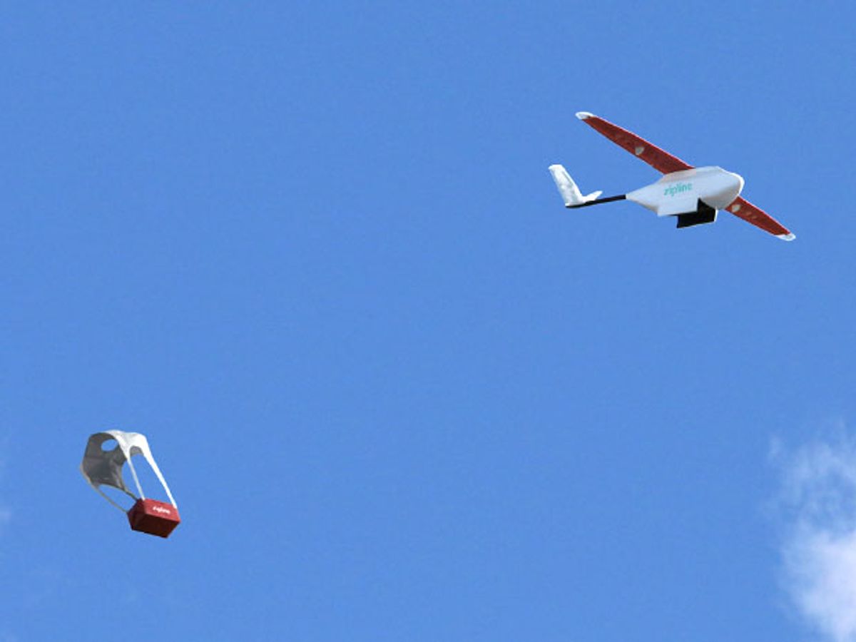 A small fixed-wing drone flies through the sky, and a small package drops slowly down to earth with a parachute attached.