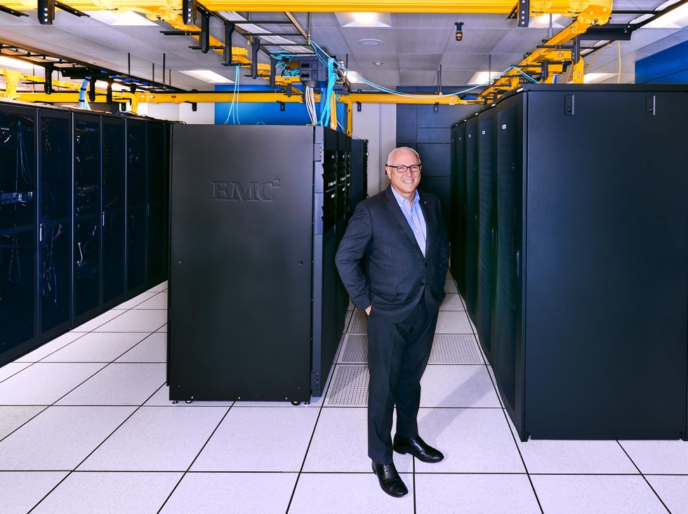 A smiling man stands in front of racks of servers