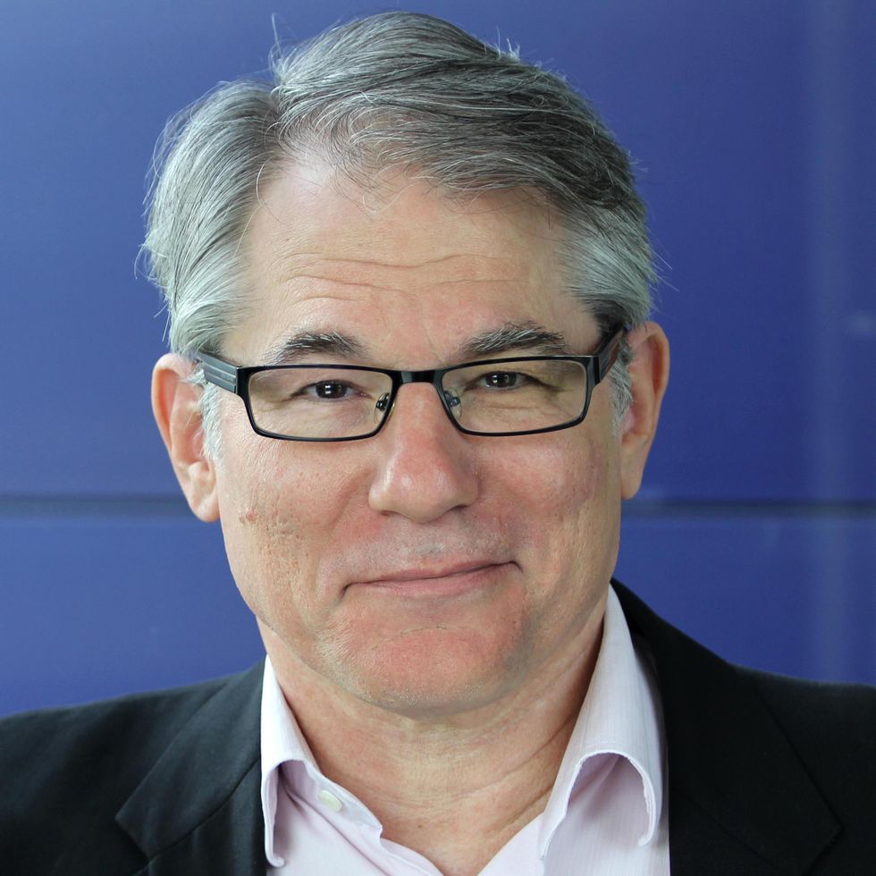 A smiling man with grey hair and glasses