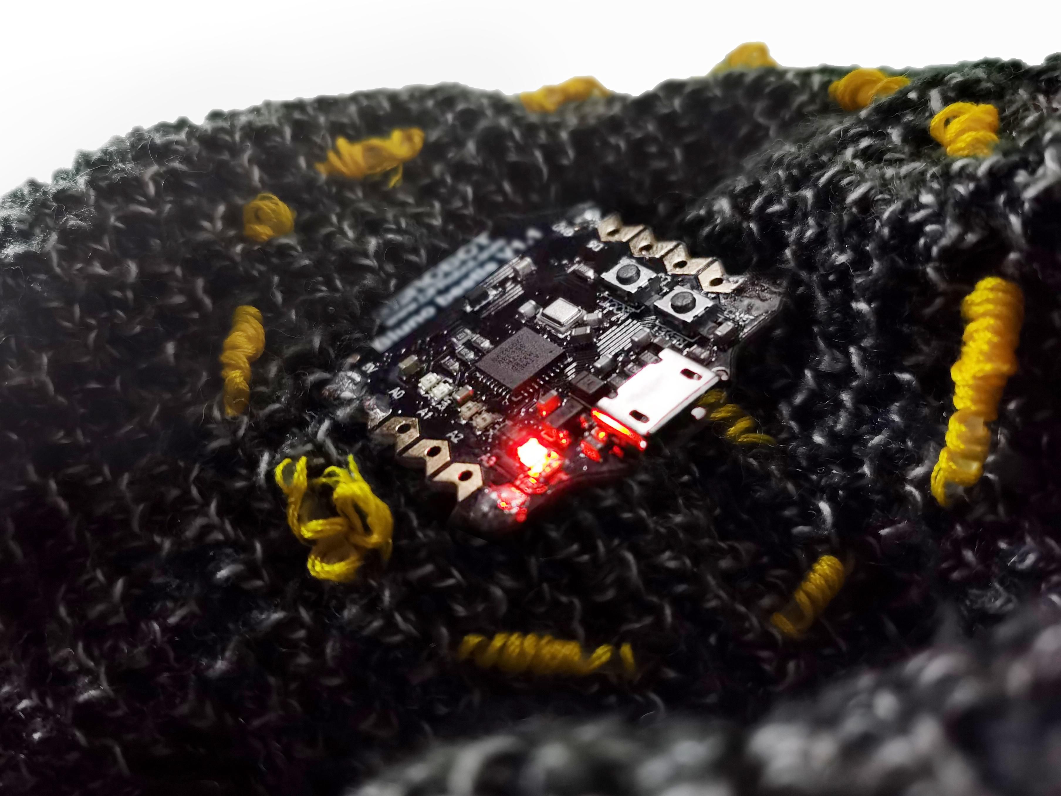 A square covered in electronics sits atop woven fabric.