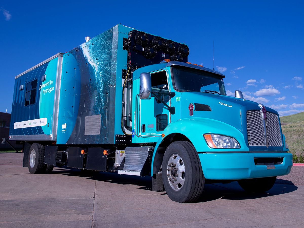 a turquoise colored box truck parked on a concrete road at a 3/4 angle 