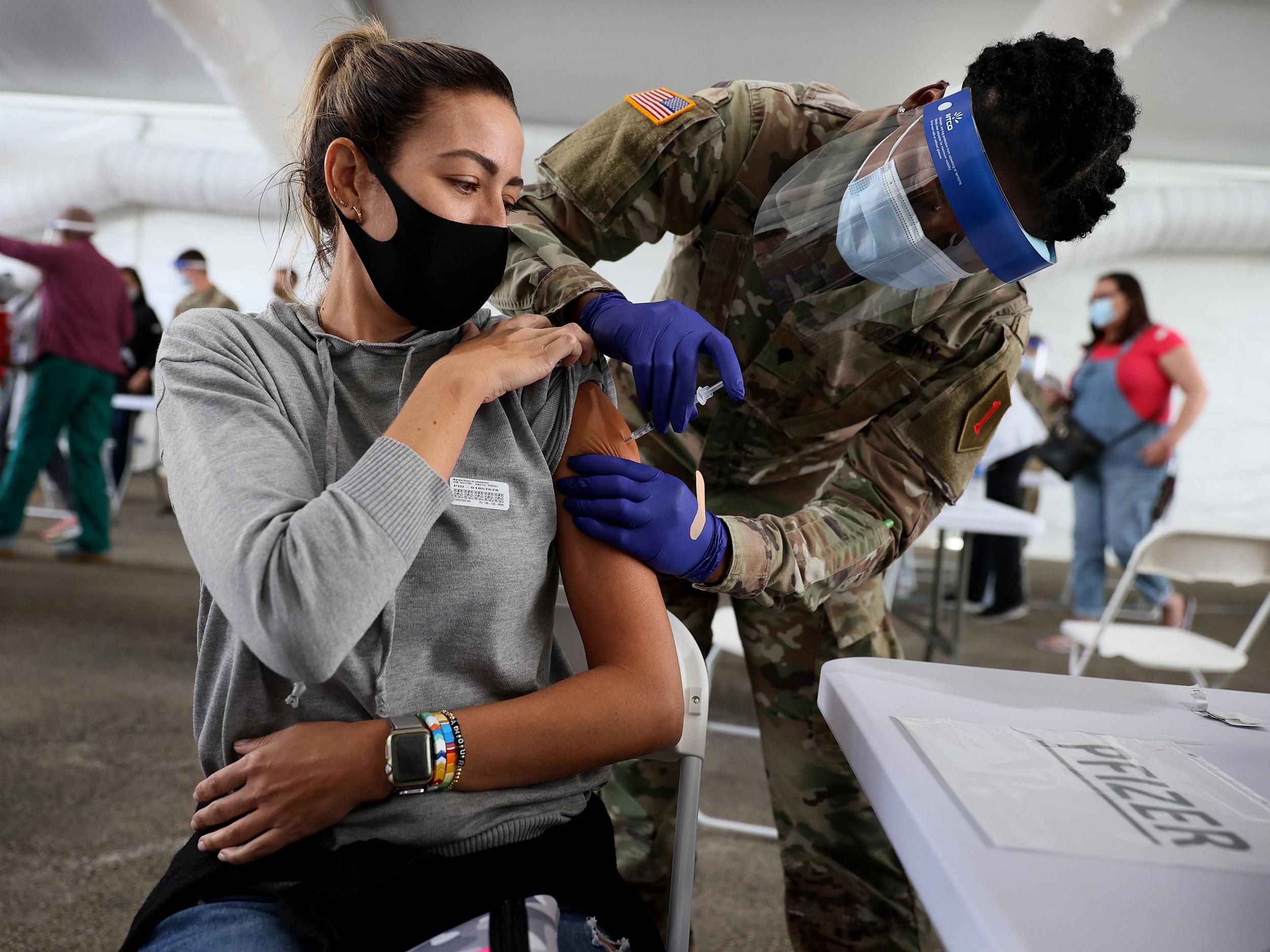 A U.S. Army soldier immunizes a woman with the Pfizer COVID-19 vaccine in North Miami, Florida. 