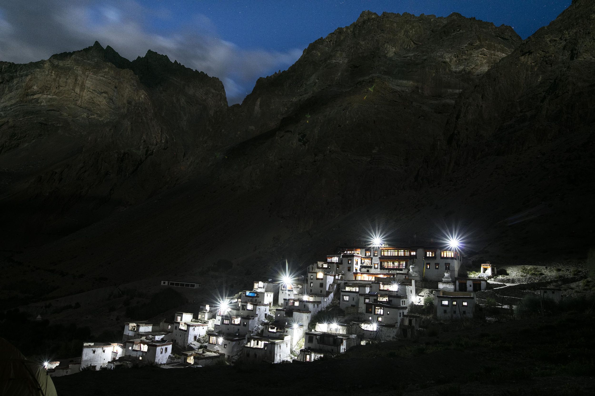 A village lit up with lights on the side of a mountain.