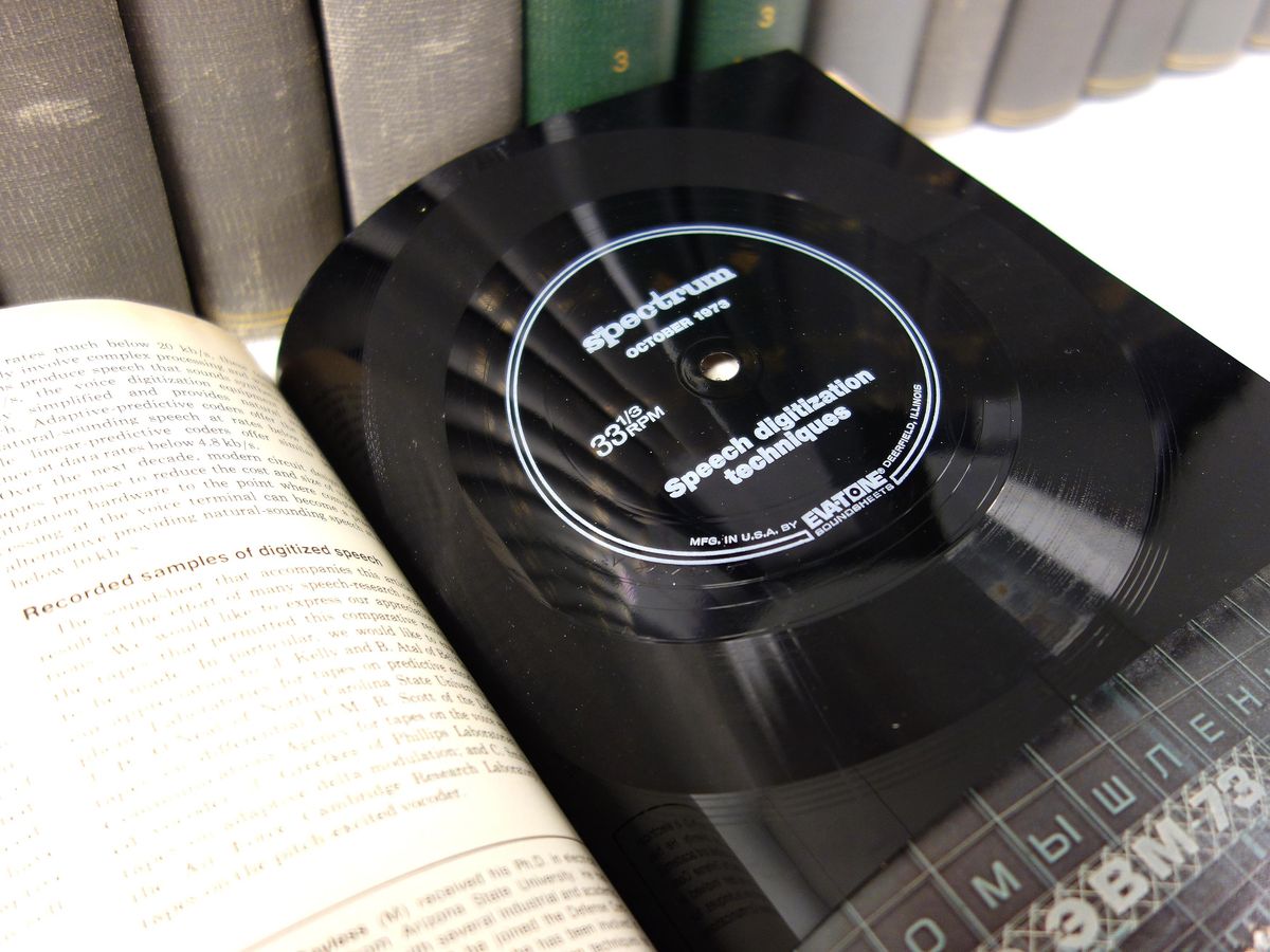 A volume of magazines lies open where a black rectangle with circular grooves has been bound in. In the center is printed "Spectrum October 1973, 331/3 RPM, Speech digitization techniques"