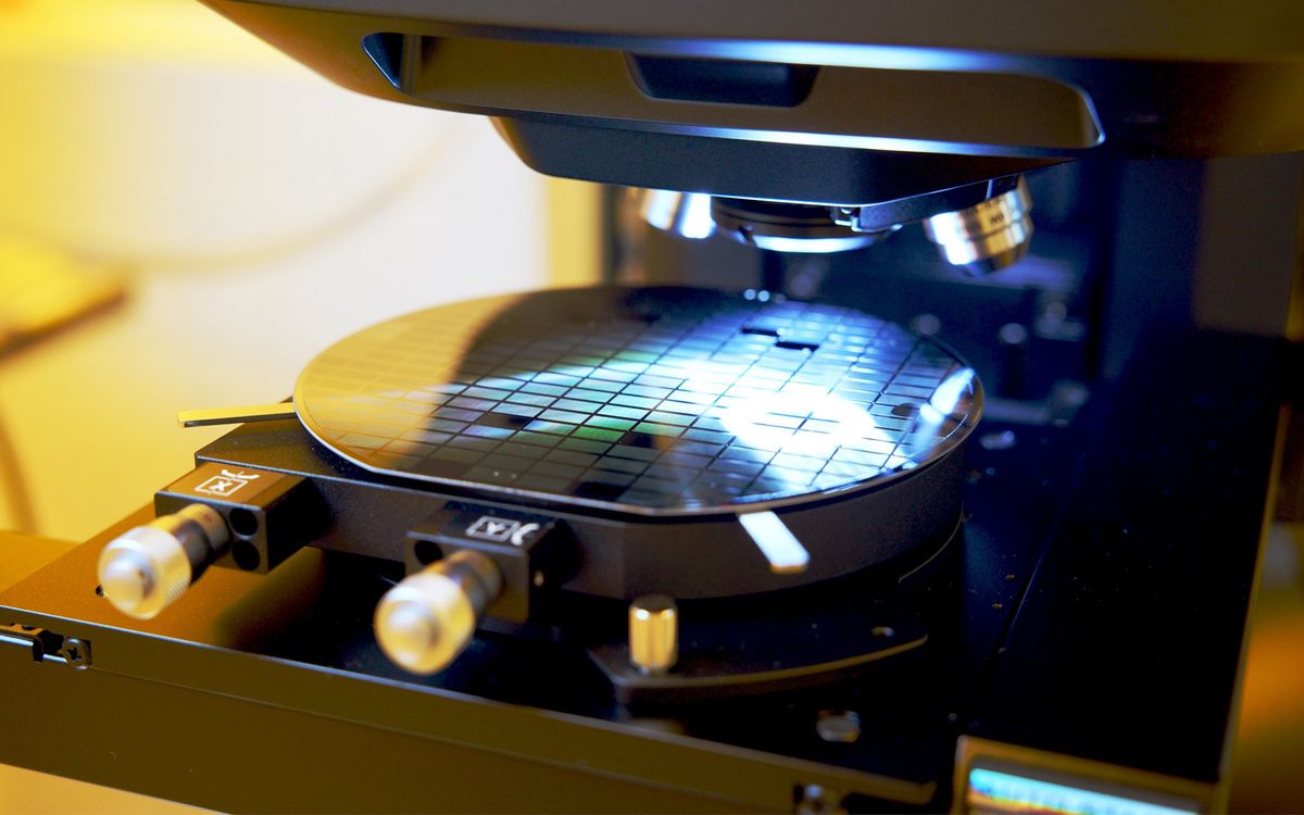 A wafer sits on a microscope platform, with light shining on it.