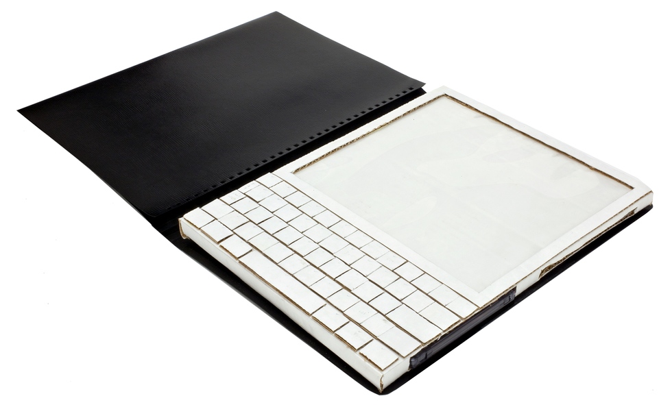 A white screen and attached computer keypad, all made of cardboard, sits inside an open black cover