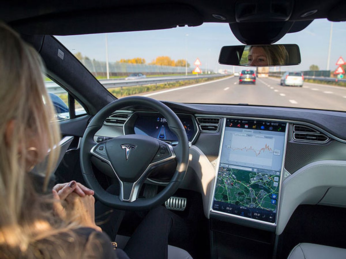 A woman in a Tesla car on Autopilot without her hands on the wheel.